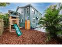Backyard with a wooden playset and a slide, surrounded by lush landscaping and mulch at 6619 Livingston N Ave, St Petersburg, FL 33702