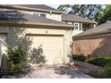 Attached garage shows neutral paint, brick, and mature landscaping at 9 Pelican Pl, Belleair, FL 33756