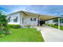 White single-wide manufactured home with carport and well-maintained landscaping at 3843 Damian Dr, Zephyrhills, FL 33541