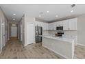Modern kitchen with white cabinets, island, and stainless steel appliances at 10985 Brightleaf Ct, Riverview, FL 33569