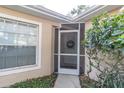 Inviting house entrance featuring a screen door, wreath, and landscaping at 4474 Connery Ct, Palm Harbor, FL 34685