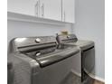 Laundry room with modern washer and dryer, and white cabinets at 4474 Connery Ct, Palm Harbor, FL 34685