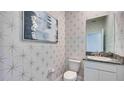 Stylish powder room with patterned wallpaper and granite vanity at 4302 Pullet Ct, Lakewood Ranch, FL 34211