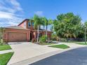 Two-story house with a two-car garage, palm trees, and a well-manicured front yard at 31982 Bourneville Ter, Wesley Chapel, FL 33543