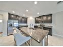 Modern kitchen featuring stainless steel appliances, a granite island, and sleek dark cabinetry at 16850 Whisper Elm St, Wimauma, FL 33598