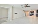 Bright, open-concept living room with tile flooring, ceiling fan, and staircase access at 16850 Whisper Elm St, Wimauma, FL 33598