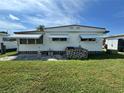 Rear view of a modest home with a small patio and spacious, grassy backyard area at 2331 Belleair Rd # Lot 237, Clearwater, FL 33764