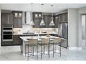 Modern kitchen with gray cabinetry, stainless steel appliances, an island with seating, and pendant lighting at 13714 Heartwood Way, Parrish, FL 34219