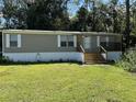 Tan single-wide mobile home with wooden steps and covered porch at 6812 Woodsman Dr, Wesley Chapel, FL 33544