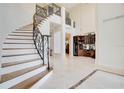 Elegant foyer featuring a curved staircase with iron railings and marble flooring at 1935 Lago Vista Blvd, Palm Harbor, FL 34685