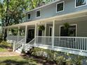 Side view of a wraparound porch featuring decorative hanging fern baskets, and meticulously maintained landscaping at 5455 Lake Le Clare Rd, Lutz, FL 33558