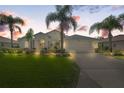 Single-Gathering home with a well-manicured lawn and palm trees at dusk at 9295 Butler Blvd, Weeki Wachee, FL 34613