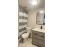 Updated bathroom with gray vanity, white toilet and striped shower curtain at 3002 W Cleveland St # E1, Tampa, FL 33609