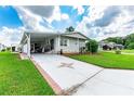 Mobile home with covered patio, landscaped yard, and driveway at 36750 Kimela Ave, Zephyrhills, FL 33542