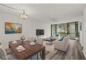 Bright, staged living room featuring an open floor plan and large windows overlooking community grounds at 14130 Rosemary Ln # 2208, Largo, FL 33774