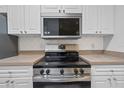 Stainless steel range and microwave in a kitchen with white cabinets at 18001 Richmond Place Dr # 511, Tampa, FL 33647