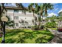Exterior view of a condo building with lush landscaping and palm trees at 2650 Countryside Blvd # F110, Clearwater, FL 33761
