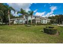 Landscaped front yard featuring a two story-home, palm trees, and a plush green lawn at 180 Keystone Palms Blvd, Tarpon Springs, FL 34688