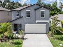 Two-story house with gray siding, white garage door, and landscaping at 6267 Back Forty Loop, Zephyrhills, FL 33541
