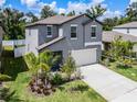 Two-story house with gray siding, white garage door, and landscaping at 6267 Back Forty Loop, Zephyrhills, FL 33541