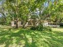 Single-story home surrounded by lush greenery and trees, providing a serene view at 26831 Chianina Dr, Wesley Chapel, FL 33544