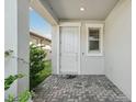 Covered front entry with a white door, brick pavers, and lush landscaping at 2848 Gridiron Isle, New Port Richey, FL 34655