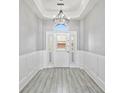 Bright entryway with white door, chandelier, and wood-look floors at 10616 Cape Hatteras Dr, Tampa, FL 33615