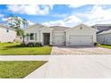 Beautiful one story home boasting a spacious three-car garage, lush green lawn and clear blue skies at 23176 Pachino Way, Lutz, FL 33549