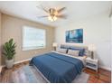 Cozy bedroom featuring a ceiling fan, plush bedding, laminate wood flooring, and neutral colored walls at 1709 E Sitka St, Tampa, FL 33604