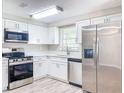 A bright kitchen with stainless steel appliances, white cabinets, laminate floors, and a double bowl sink at 1709 E Sitka St, Tampa, FL 33604
