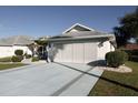 White house with attached two-car garage, landscaping, and a paved driveway at 2451 E Del Webb Blvd, Sun City Center, FL 33573