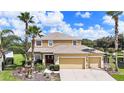 Two-story house with a three-car garage, landscaping, and palm trees at 5806 Candytuft Place, Land O Lakes, FL 34639