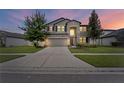 Two-story house with gray siding, stone accents, and a three-car garage at dusk at 19065 Malinche Loop, Spring Hill, FL 34610