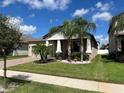 Tan house with beige garage door, landscaping, and palm trees at 13240 Satin Lily Dr, Riverview, FL 33579