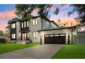 Exterior elevation of a two-story home featuring modern architecture, dark trim, manicured lawn and attached garage at 4625 W El Prado Blvd, Tampa, FL 33629