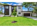 Modern two-story home with dark accents, attached garage, well-maintained lawn, and mature trees under a blue sky at 4625 W El Prado Blvd, Tampa, FL 33629