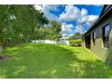 Spacious backyard with a large grassy area, mature trees, and a white vinyl fence at 2727 Colewood Ln, Dover, FL 33527