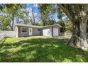 Gray house with a white door and walkway, surrounded by lush green grass and trees at 7694 62Nd N St, Pinellas Park, FL 33781