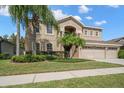 Charming two-story home featuring a three-car garage, lush lawn, and mature palm trees at 17905 Machair Ln, Land O Lakes, FL 34638