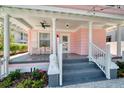 Inviting front porch with rocking chairs and grey steps leading to charming pink house at 963 Highland Ave, Dunedin, FL 34698