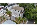 Aerial view of a three-story gray home showcasing a charming balcony, palm trees, and lush greenery at 1408 W Azeele St, Tampa, FL 33606