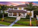 Two story house with a large front porch, lush landscaping, and a gated entrance at 2030 Coffee Pot Ne Blvd, St Petersburg, FL 33704