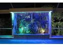 Stunning illuminated waterfall feature adjacent to a pool and spa at 5909 Menorca Ln, Apollo Beach, FL 33572