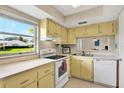 Bright kitchen with yellow cabinets, white appliances, and a view from the window at 3365 39Th S St # C-1, St Petersburg, FL 33711
