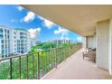 Spacious balcony with seating offers serene views of lush greenery and distant buildings against a bright sky at 220 Belleview Blvd # 802, Belleair, FL 33756