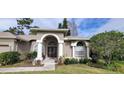 Tan two-story house with a three car garage and lush landscaping at 4467 Worthington Ct, Palm Harbor, FL 34685