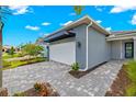 Modern home with gray exterior and paver driveway at 11216 Livewell Ct, Venice, FL 34293