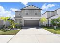 Two-story home with gray exterior, two-car garage, and landscaping at 16764 Delia St, Wimauma, FL 33598