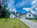 Beautiful home featuring white siding, gray trim, stone accents, a manicured lawn, and an attached two-car garage at 4000 Southern Valley Loop, Brooksville, FL 34601