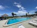 Community pool with lounge chairs and shade structures for relaxation and enjoyment on a sunny day at 428 Windrush Bay Dr, Tarpon Springs, FL 34689